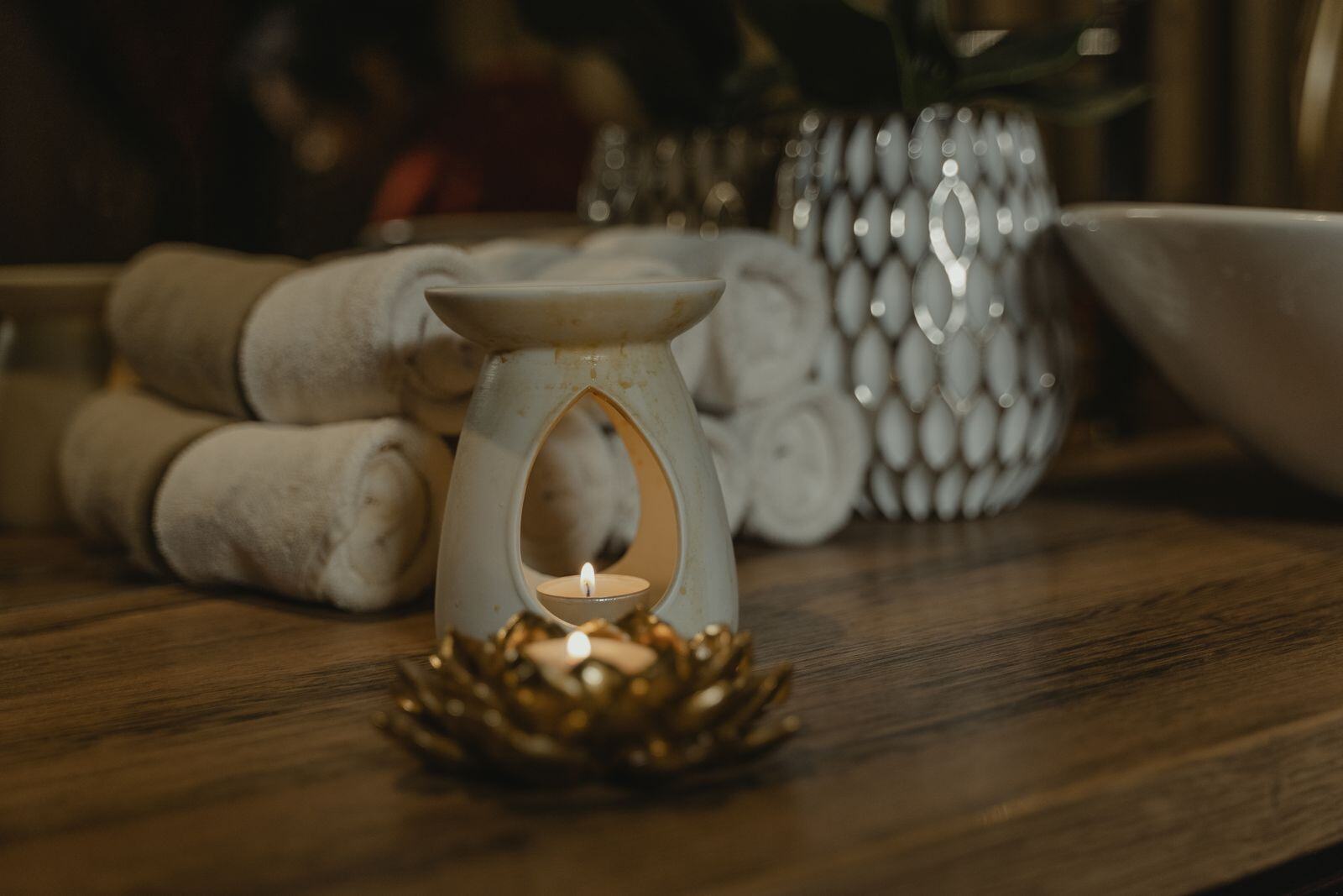 Aromatherapy oil burner and rolled towels in a calm massage room