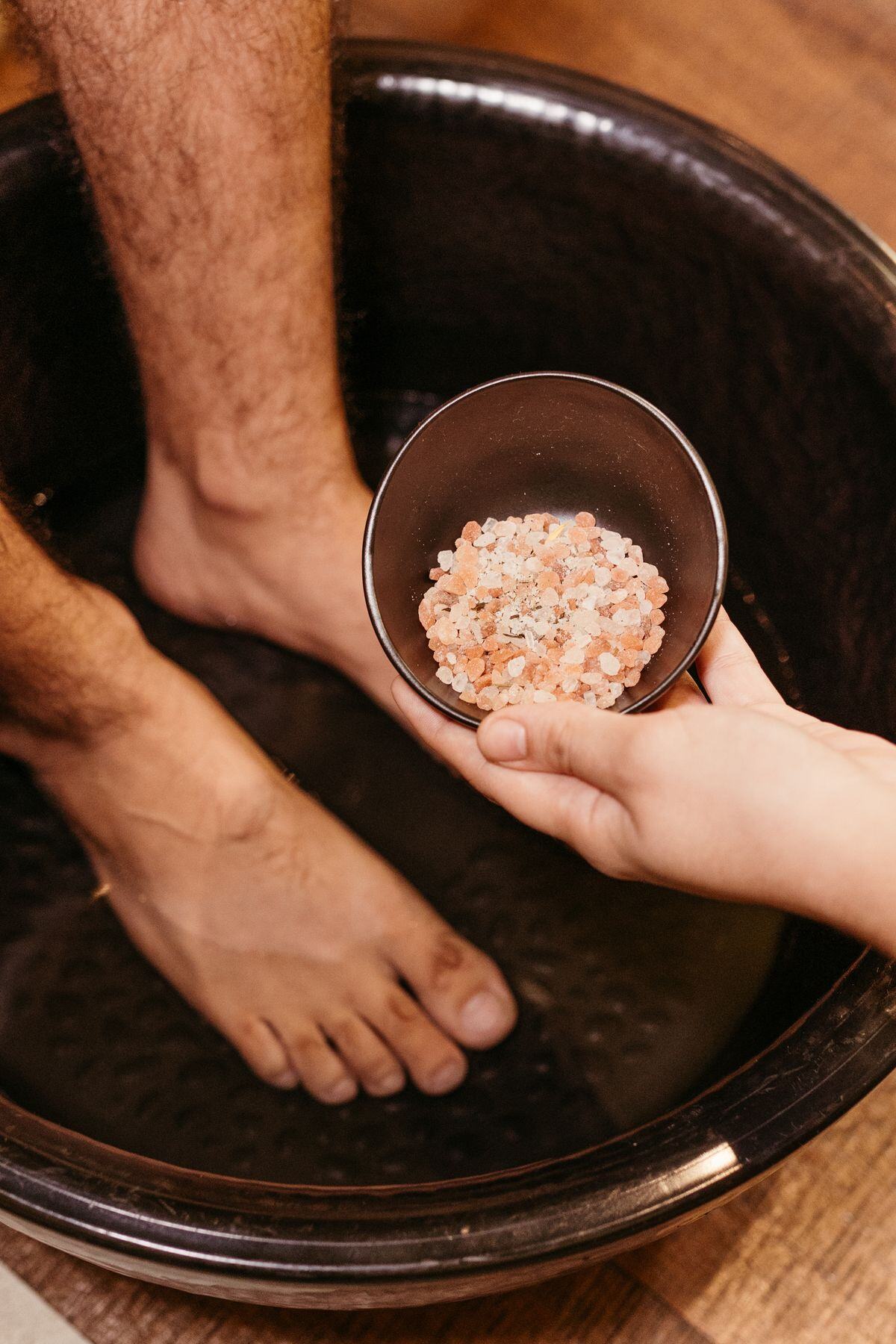 Mineral bath salts poured into a wooden foot basin for a herbal foot soak